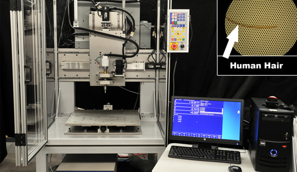 CNC drill pattern viewed under magnification showing human hair for scale.